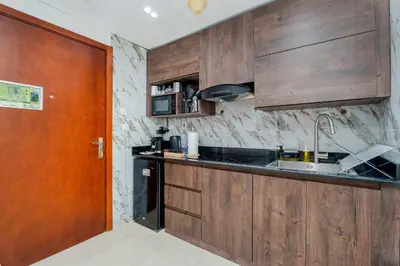 a kitchen with wooden cabinets and a wooden door at Modern 1BR with City View - Balcony - Near Metro in Dubai