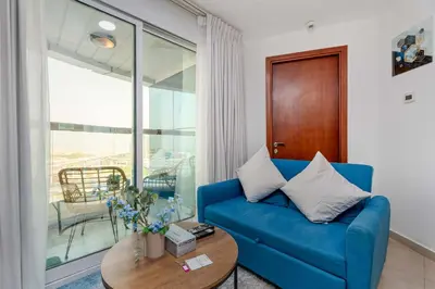 a living room with a blue couch and a table at Modern 1BR with City View - Balcony - Near Metro in Dubai