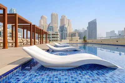a swimming pool with two white chairs and a city skyline at Inviting Dubai Marina Studio near Beach and Canal in Dubai