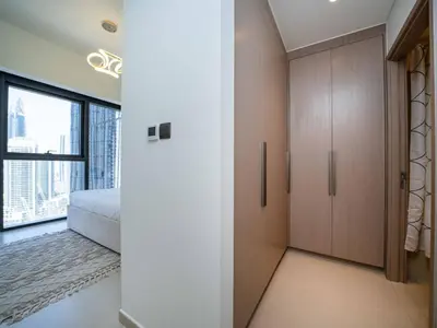 a bedroom with a bed and a closet with a window at Stunning 2 bed dubai mall burj khalifa downtown ACT 1 in Dubai