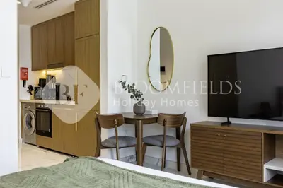 a bedroom with a table with two chairs and a tv at Bloomfields Supreme Stu In Azizi Riviera in Dubai