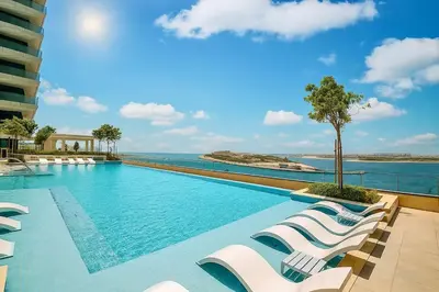 a swimming pool with lounge chairs and the ocean at Serene Ocean Views 2BR Emaar Beachfront in Dubai