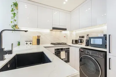 a kitchen with white cabinets and a washer and dryer at Serene and Stylish Home in the Heart of JVC in Dubai