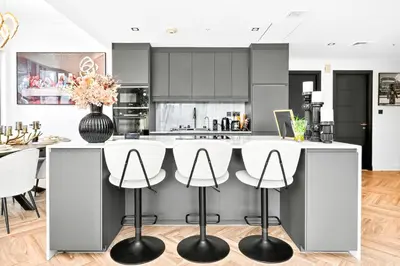 a kitchen with white counters and white stools at Stunning 2 Bdr Luxury Burj Khalifa view in Dubai
