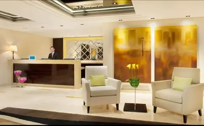 a man standing in a lobby with two chairs and a television at Luxury Studio with Pool, Gym & Downtown Access in Dubai