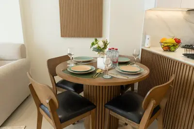 a wooden table with chairs and plates and wine glasses at Binghatti Amber in JVC, 15 Min to Marina in Dubai