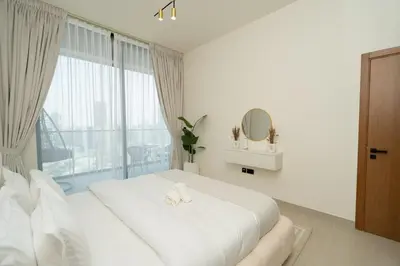 a white bedroom with a large bed with a window at Binghatti Amber in JVC, 15 Min to Marina in Dubai