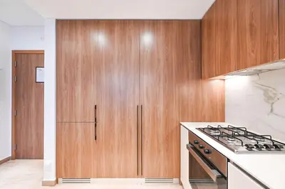 a kitchen with wooden cabinets and a stove at Modern 1BR w Balcony & Great Amenities JVC in Dubai