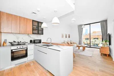 a kitchen with white appliances and a living room at Modern 1BR w Balcony & Great Amenities JVC in Dubai