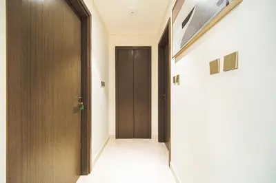 a hallway with a brown door and a white floor at SettlerHomes - 14F Ocean View Gem With Private Beach in Dubai