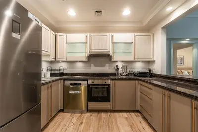 a kitchen with white cabinets and a stainless steel refrigerator at Spacious 2 bedroom apartment I Palm Jumeirah in Dubai