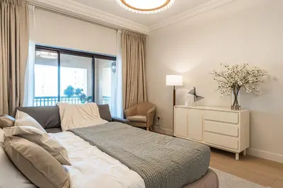 a bedroom with a bed and a dresser and a window at Spacious 2 bedroom apartment I Palm Jumeirah in Dubai