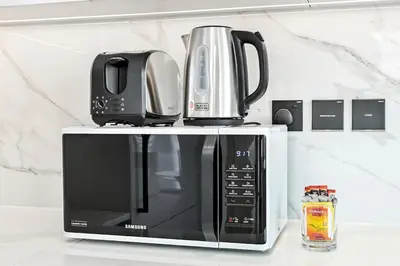 a microwave with a coffee pot on top of it at Golden Stays - Private Pool in Binghatti Gardenia I Modern 2BR Escape in Dubai