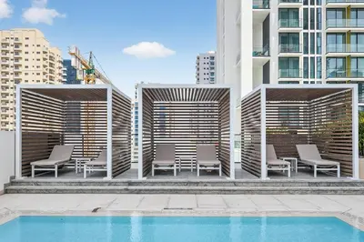 a group of chairs and a pool in front of a building at Golden Stays - Private Pool in Binghatti Gardenia I Modern 2BR Escape in Dubai