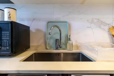 a kitchen counter with a sink and a microwave at White Sage Modern Studio in JVC with Balcony and City Views in Dubai
