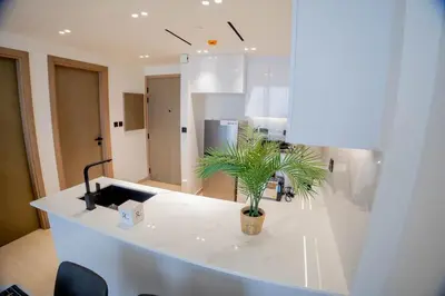 a white kitchen with a palm plant on a counter at Binghatti Corner in Dubai