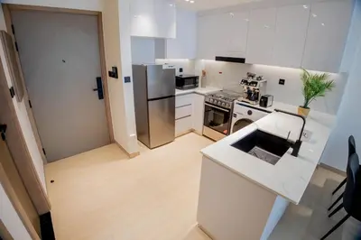 a kitchen with white cabinets and stainless steel appliances at Binghatti Corner in Dubai