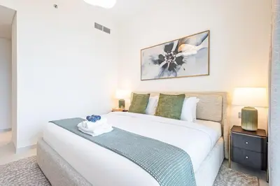 a bedroom with a large white bed and two lamps at Elegant 2BR, Grand Bleu, Coastal Elegance in Dubai