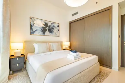 a bedroom with a large white bed and a wooden door at Elegant 2BR, Grand Bleu, Coastal Elegance in Dubai