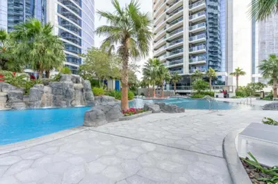 a swimming pool with palm trees and buildings at Luxury 1BHK in Damac Paramount Towers, Business Bay in Dubai