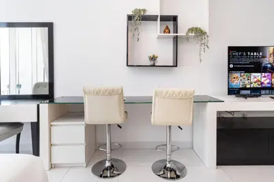 an office with a desk and two white chairs at Sleek and Spacious Sports City Studio in Dubai
