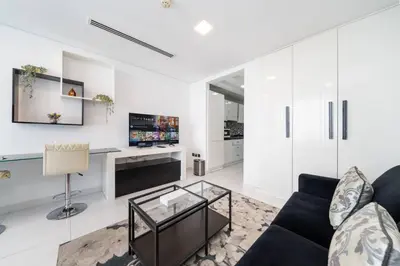 a living room with a couch and a glass table at Sleek and Spacious Sports City Studio in Dubai