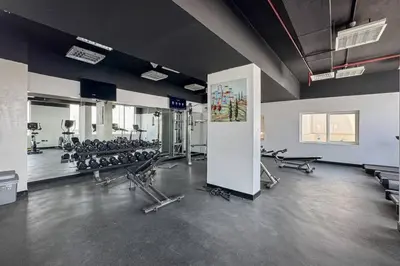 a gym with several treadmills and machines in a room at Sleek and Spacious Sports City Studio in Dubai
