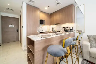 a kitchen with a counter and chairs in a room at Stylish Studio in JVC Bright, Cozy and Convenient in Dubai