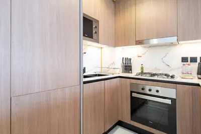 a kitchen with wooden cabinets and an oven at Stylish Studio in JVC Bright, Cozy and Convenient in Dubai