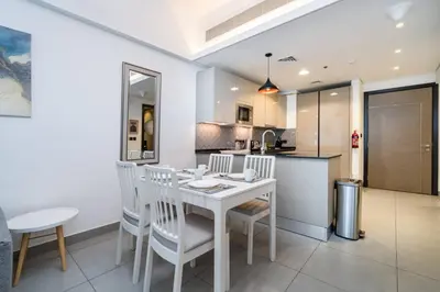 a kitchen and dining room with a white table and chairs at Modern JVC 1-Bed Pool, Gym and Family Amenities in Dubai