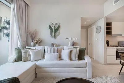 a living room with a white couch and a kitchen at Boho Comfort - 1BR with Gym, Pool, Tennis, Yoga and Dubai Mall access in Dubai
