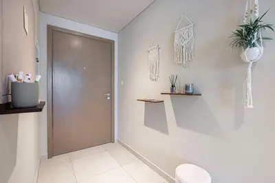 a bathroom with a brown door and a white wall at Boho Comfort - 1BR with Gym, Pool, Tennis, Yoga and Dubai Mall access in Dubai
