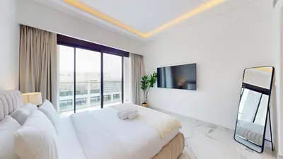 a white bedroom with a large bed and a large window at Azizi Riviera 61 - Serene Studio in Meydan in Dubai