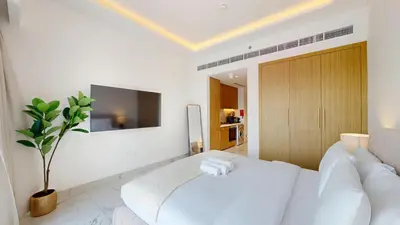 a white living room with a white couch and a tv at Azizi Riviera 61 - Serene Studio in Meydan in Dubai
