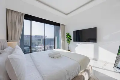 a white bedroom with a large bed and a large window at Azizi Riviera 61 - Serene Studio in Meydan in Dubai