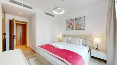 a bedroom with a large white bed with a red blanket at Vacationer Chic 1 Bedroom Creek Harbour in Dubai