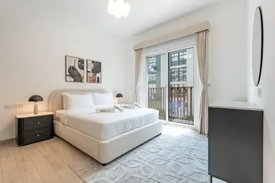 a white bedroom with a bed and a large window at Contemporary 1Bedroom Escape in Eaton Place in Dubai