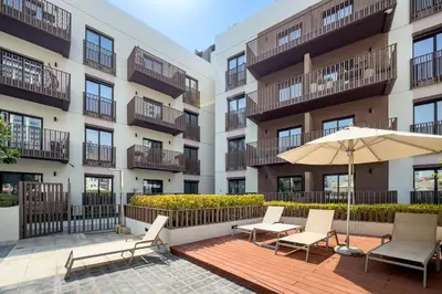 an apartment patio with chairs and an umbrella at Contemporary 1Bedroom Escape in Eaton Place in Dubai
