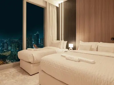 two beds in a hotel room with a view of a city at Forte Suites by Prestige Nest in Dubai