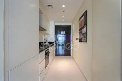 a hallway leading to a kitchen with white walls at Elegant Studio apartment in Avanti Tower Business Bay in Dubai