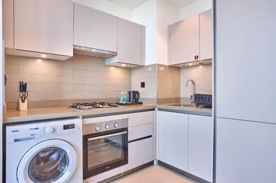 a kitchen with white cabinets and a washer at STAY BY LATINEM Luxury 1BR Holiday Home CVR A511 near Downtown in Dubai