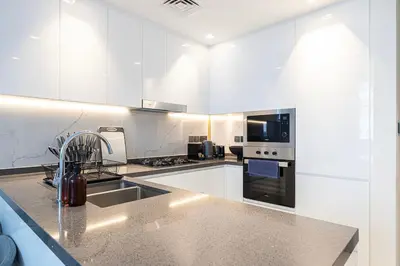 a white kitchen with a sink and a stove at Park Views by Samana with Private Pool in Dubai