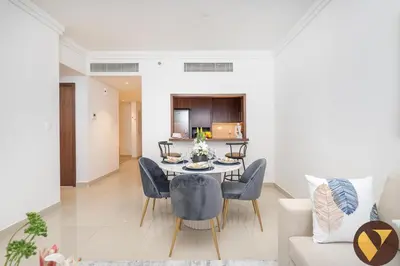 a dining room and living room with a table and chairs at Vogue Downtown Boulevard Point near Burj Khalifa and Dubai Mall, One Bedroom Apartment with Burj Khalifa view from the Balcony and Access to all Amenities in Dubai
