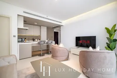 a living room with a table and chairs and a kitchen at LUX The West Avenue Dubai Marina Suite in Dubai