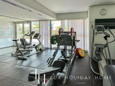 a gym with several treadmills and machines in a room at LUX The West Avenue Dubai Marina Suite in Dubai