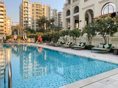 a large swimming pool with chairs and buildings at FIRST CLASS 2BR Creek Beach Comfort & Style in Dubai