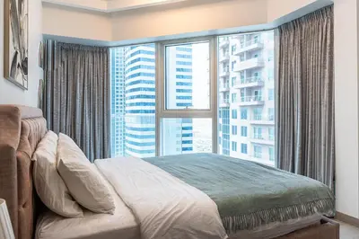 a bedroom with a bed and a large window at Spacious 2 Bedrooms with maid room I JLT in Dubai