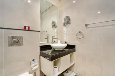 a bathroom with a sink and a mirror at White Sage Damac Hills Cozy Artesia Studio in Dubai