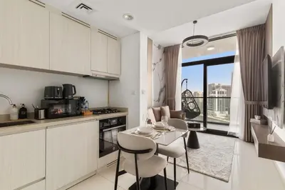 a kitchen with white cabinets and a table and chairs at Zarela Luxe with River Views in Dubai