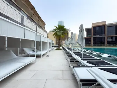 a row of chaise lounge chairs next to a swimming pool at GuestReady - 1BR l Canal View | Near Dubai Mall in Dubai